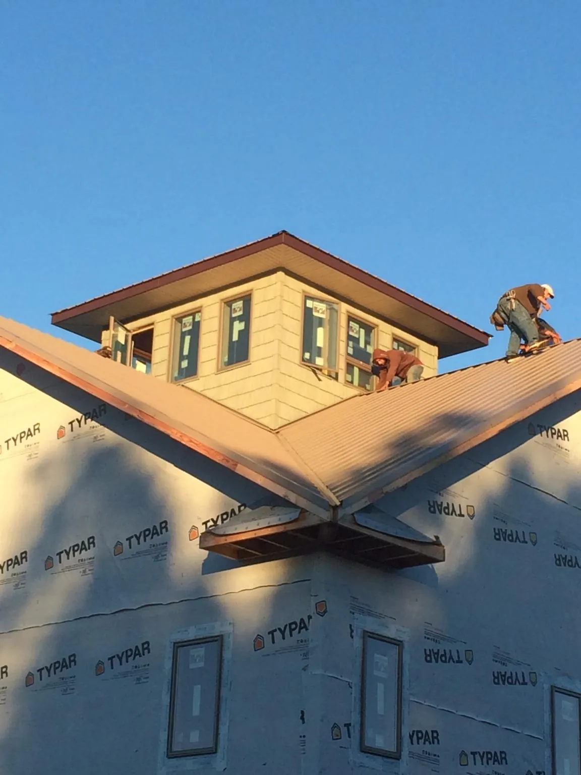 Roofers working around a rooftop cupola on a new metal roof at sunset — Roof Waterproofing in Bennett by Roofing Brothers